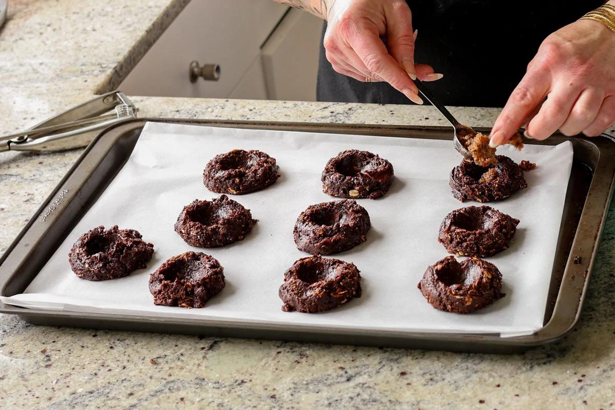 pressing wells into the centers of the unbaked German chocolate cookies