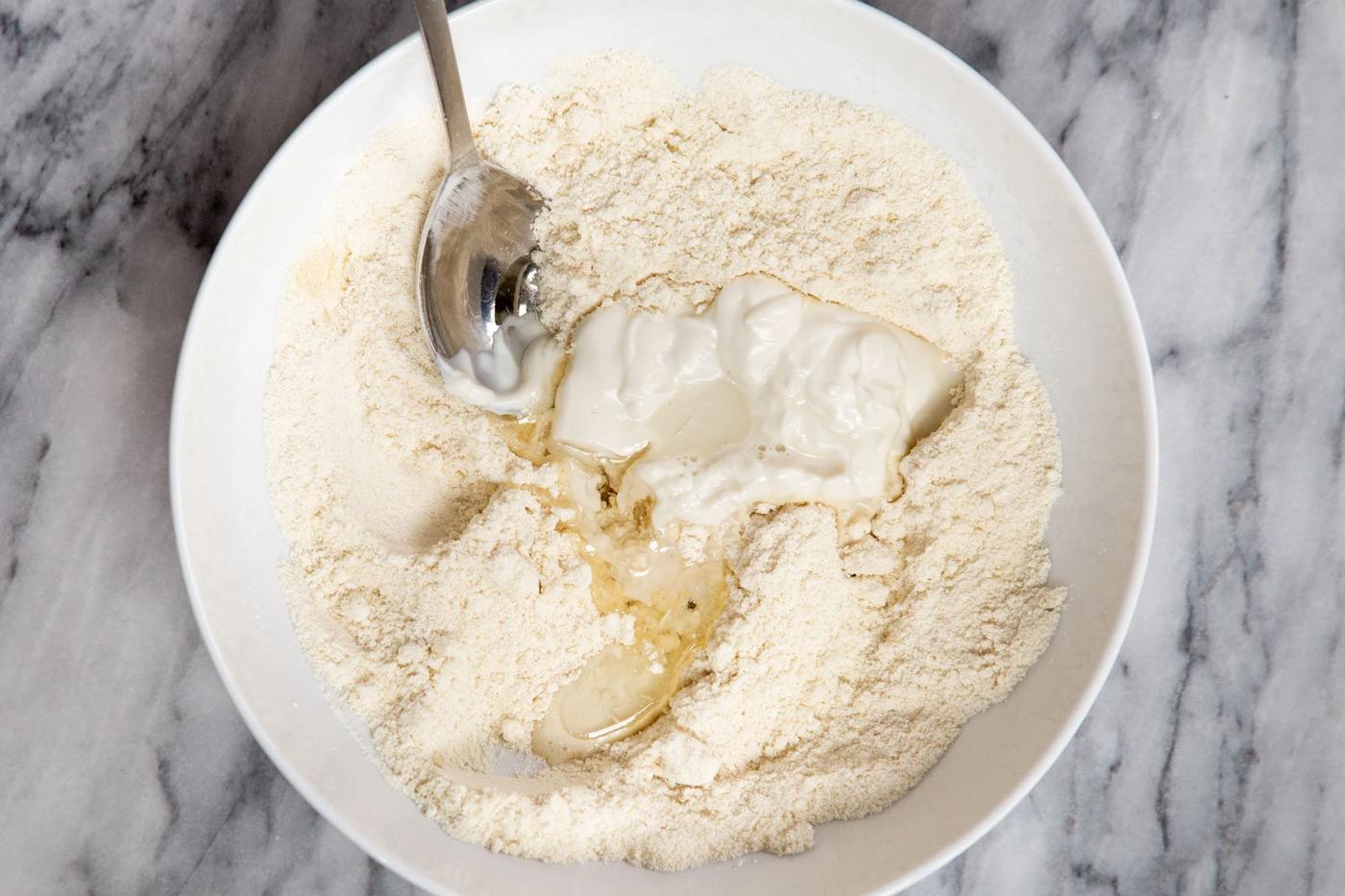 vegan yogurt and milk being added to dry naan ingredients