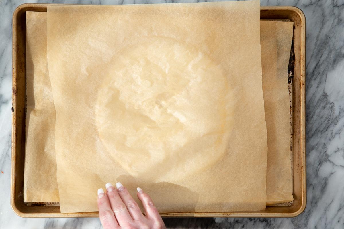 parchment paper being placed on an round of almond flour pizza crust