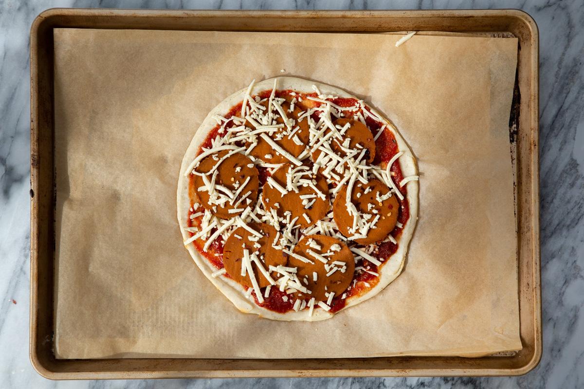 almond flour pizza crust being topped with pepperoni and cheese