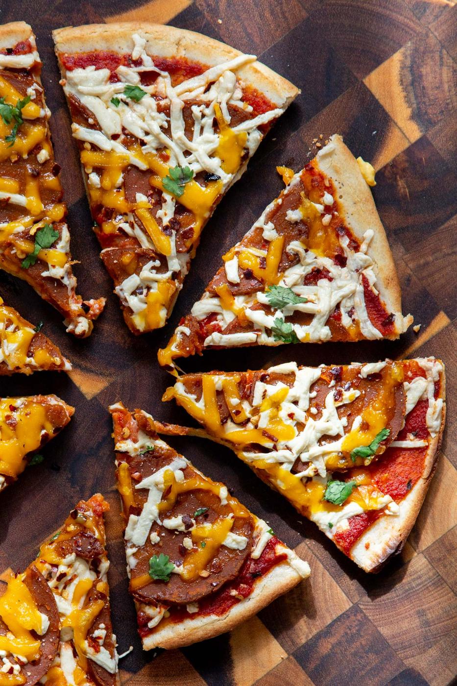sliced vegan almond flour crust pizza on a wooden chopping board