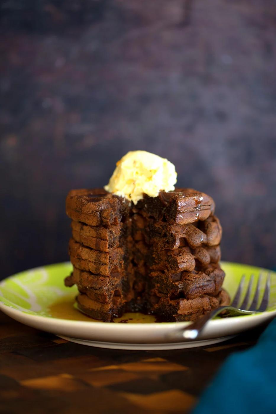 a stack of buckwheat waffles topped with vanilla ice cream with a corner cut out