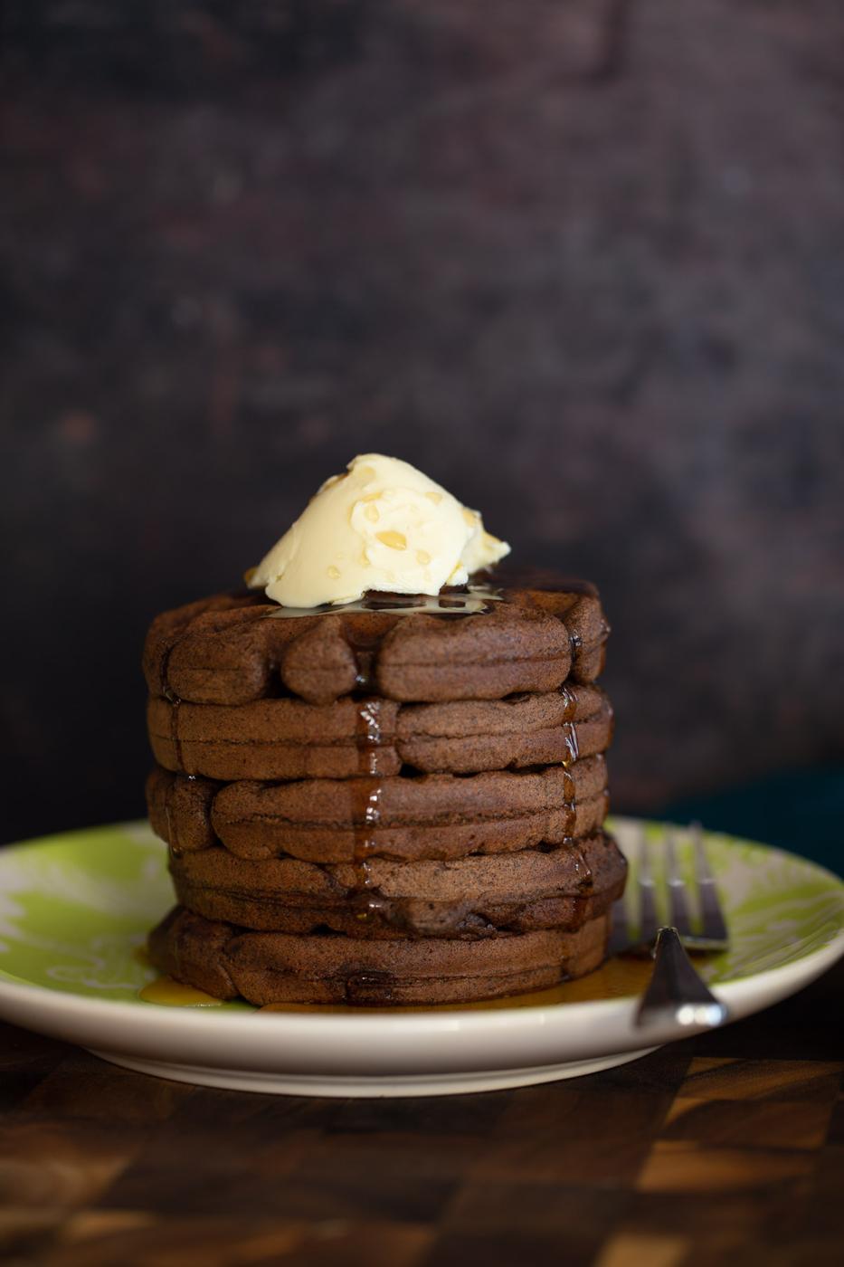 side view of a stack of chocolate buckwheat waffles topped with vanilla ice cream