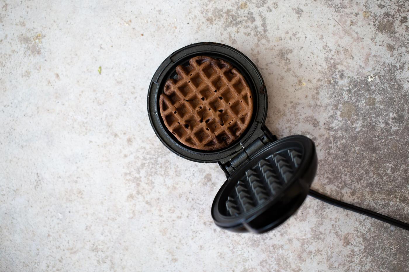overhead shot of a waffle iron with a buckwheat waffle in it