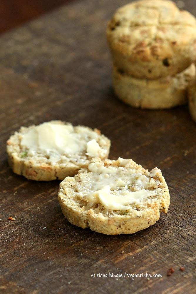 a halved vegan and gluten-free biscuit served on a wooden board with a smear of butter