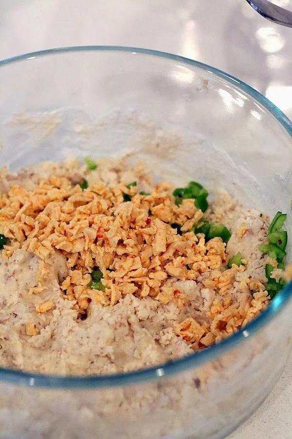 vegan pepper jack shreds and chopped jalapenos being added to gluten-free biscuits dough