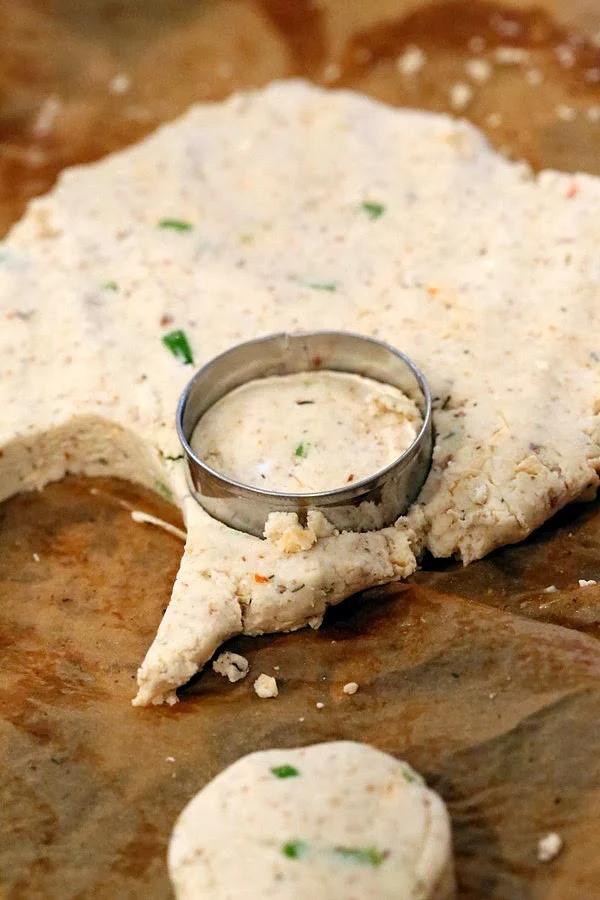 gluten-free cheese biscuits being cut out using round metal cookie cutters