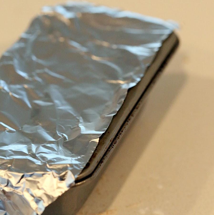 aluminum foil being placed over baking pan to prevent gluten-free cheese biscuits from drying out