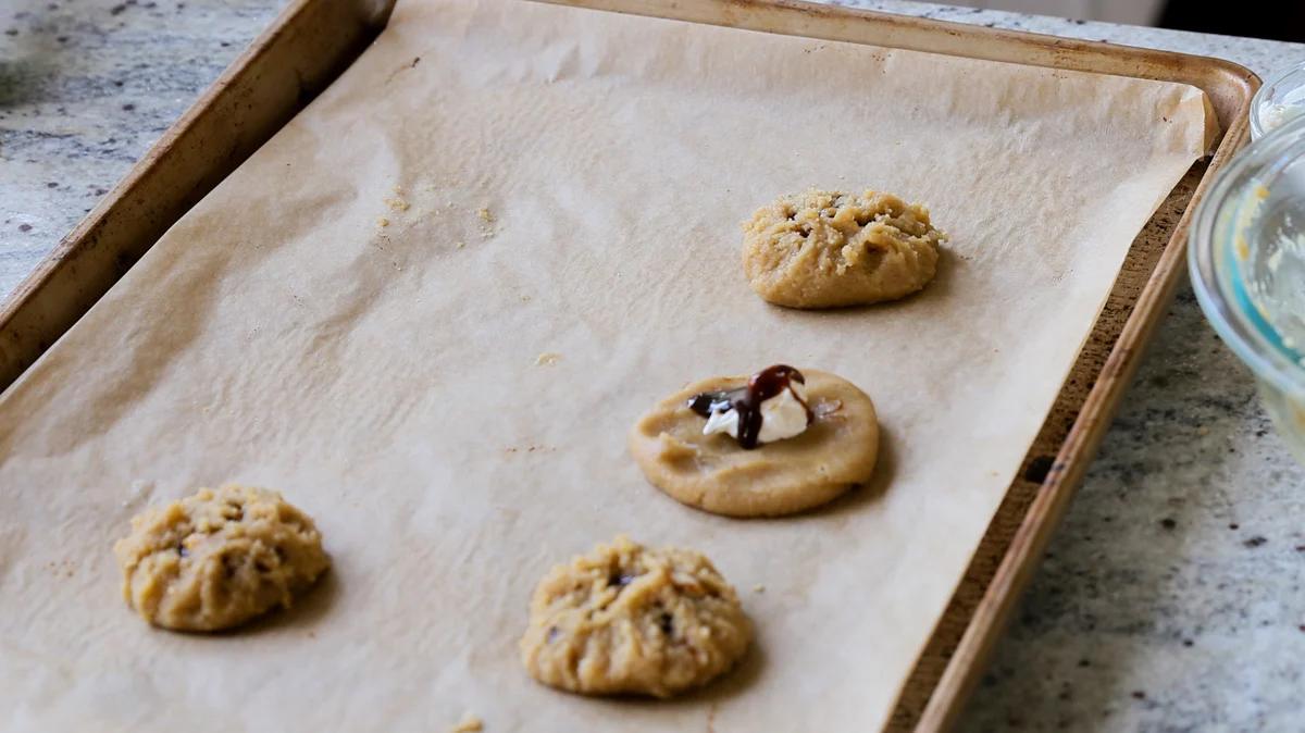 adding the caramel sauce over the cream cheese in one open cookie