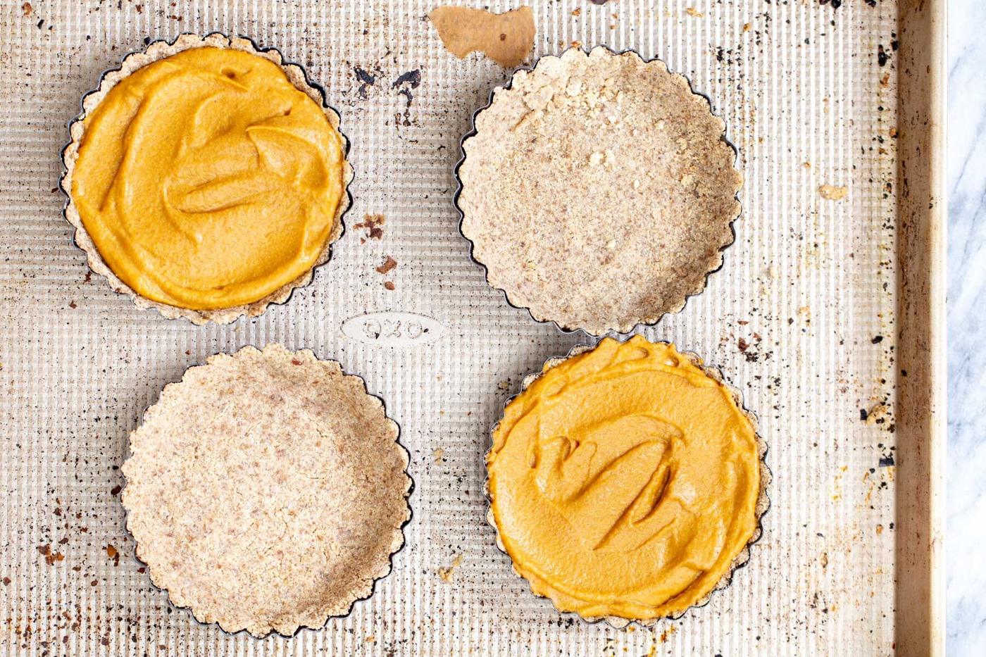 individual pumpkin pies on a baking sheet
