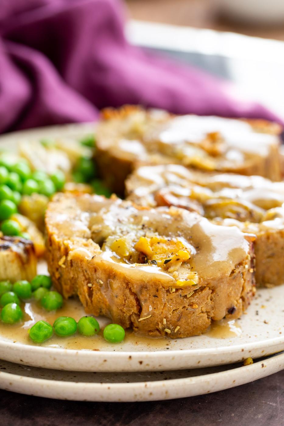 three slices of vegan holiday nut roast filled with roasted vegetables