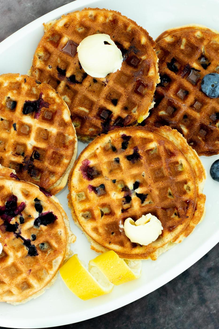 vegan glutenfree Lemon Blueberry Waffles on a platter served with dollops of butter