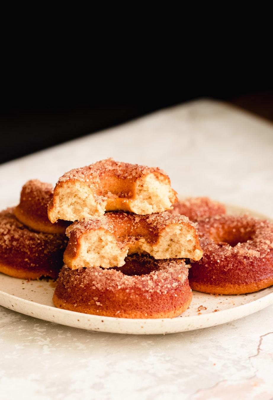 side view of a plate with glutenfree vanilla donuts with one donut being cut into half