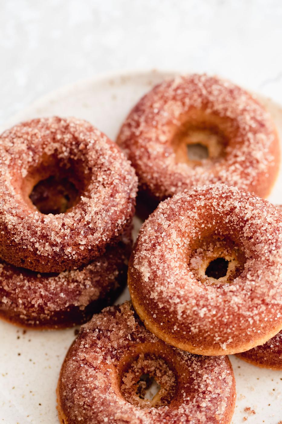vegan glutenfree vanilla donuts with cinnamon sugar topping on a white plate