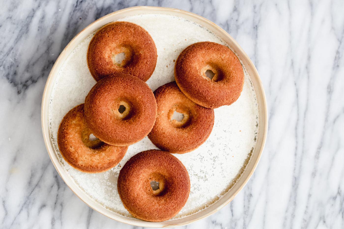 overhead shot of a white plate with glutenfree donuts on a marble kitchen table