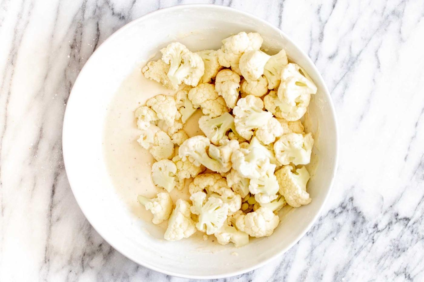 cauliflower in the bowl with the batter before tossing together