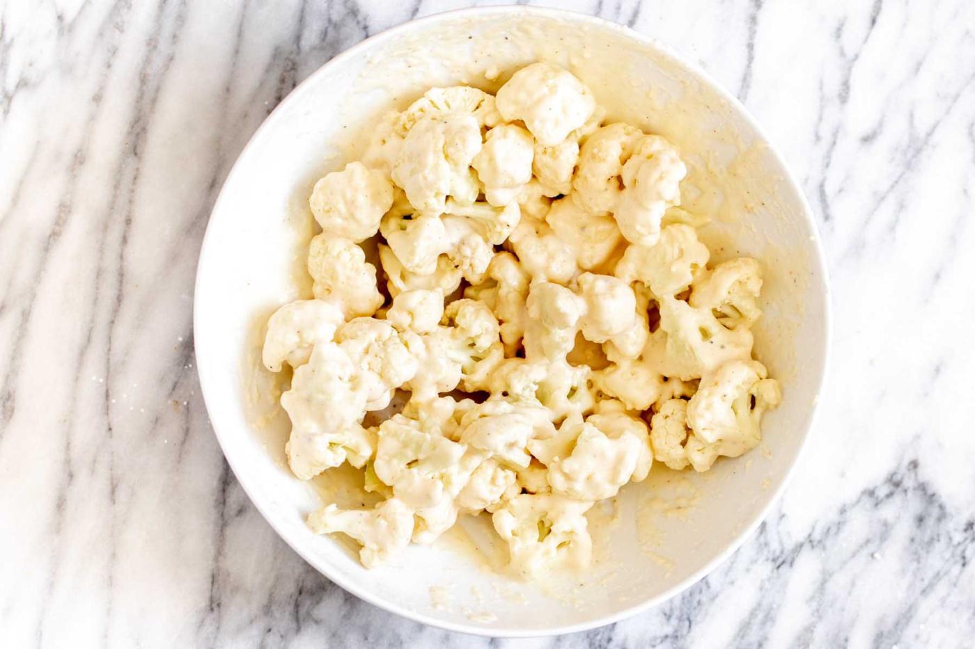 cauliflower in the bowl with the batter after tossing together