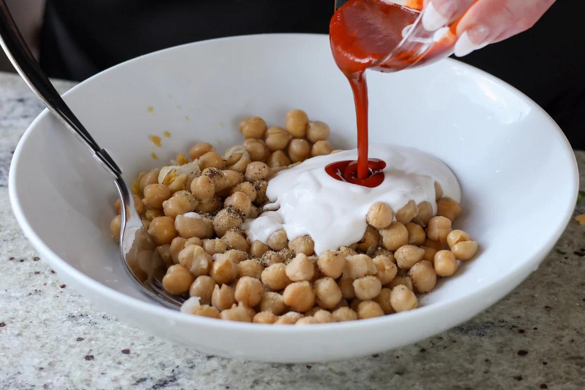adding vegan mayo and gochujang to the chickpeas