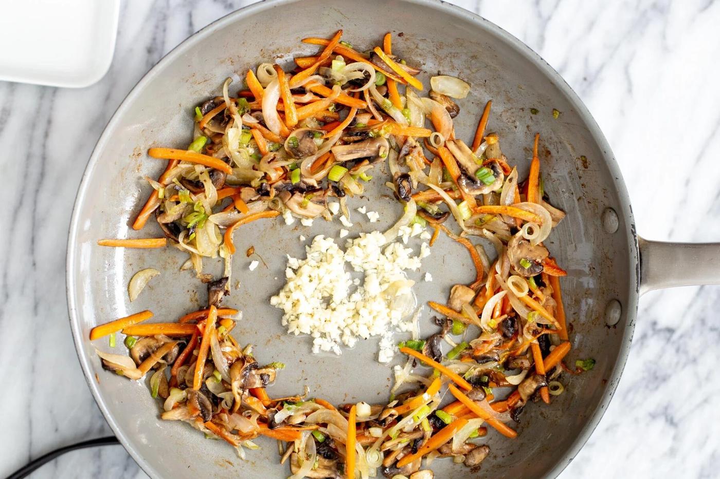 finely sliced veggies stir-frying with garlic in a saucepan