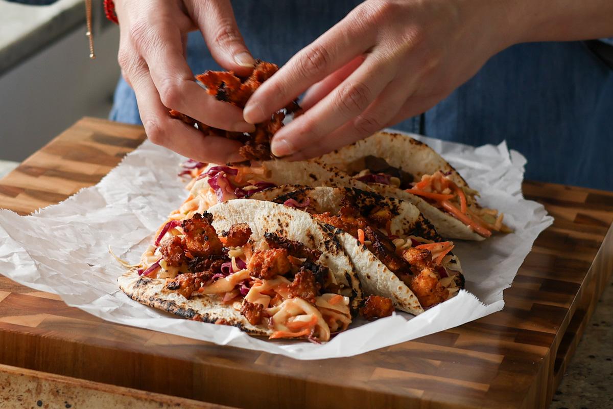 adding the gochujang tofu to the tacos