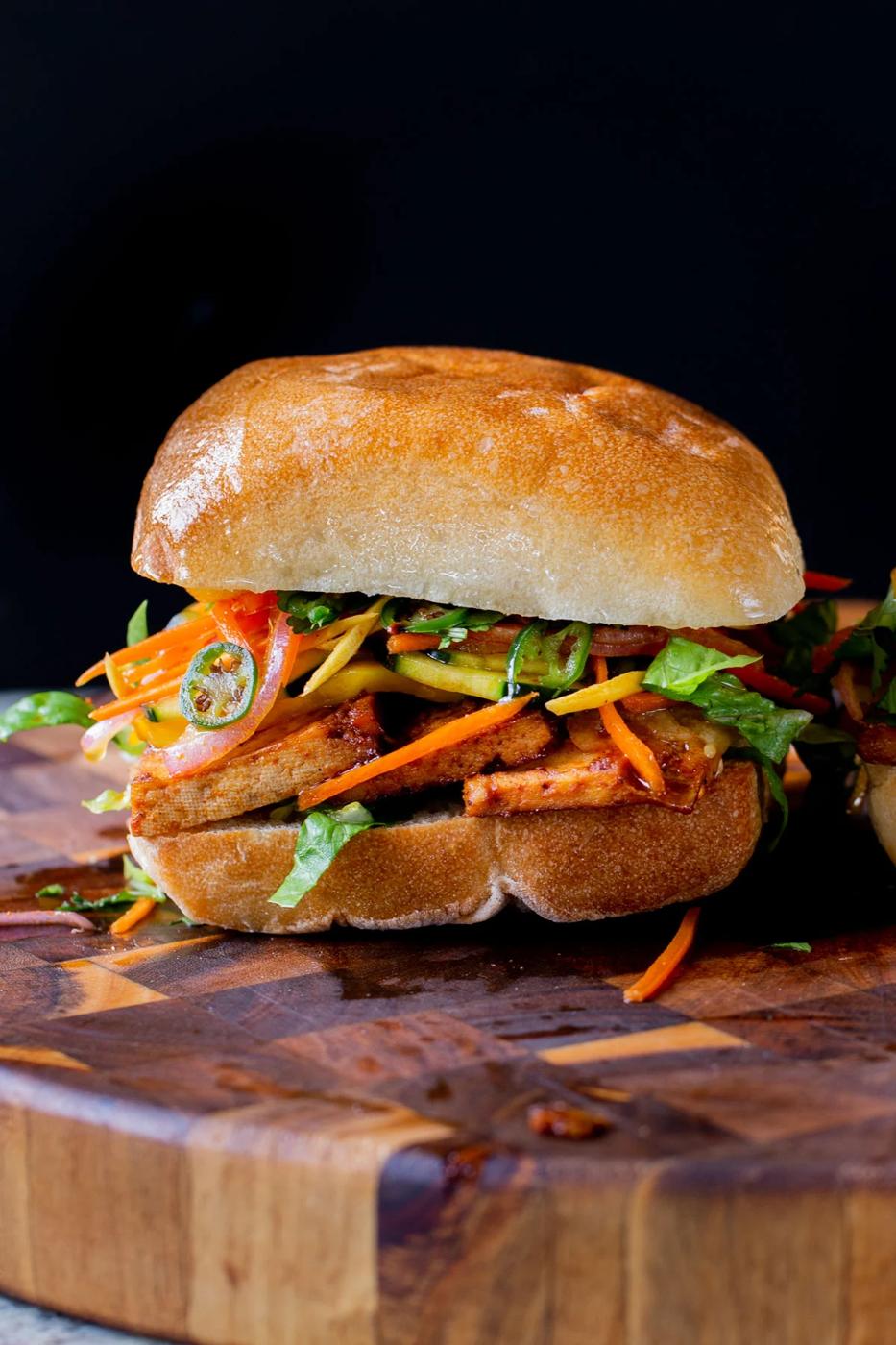 gochujang tofu banh mi with pickled veggies on a wooden cutting board