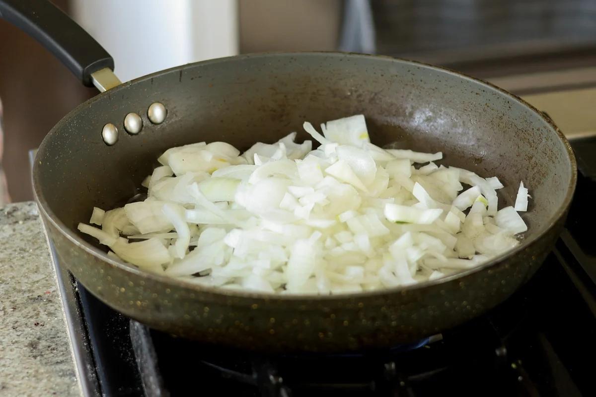 Sliced onions in a black skillet.