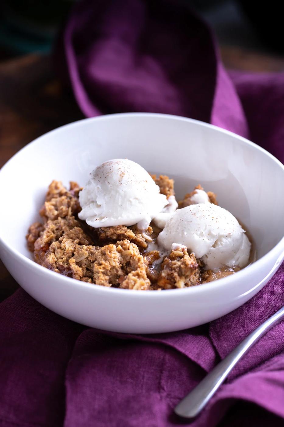a serving of apple pear crisp topped with two scoops of ice cream