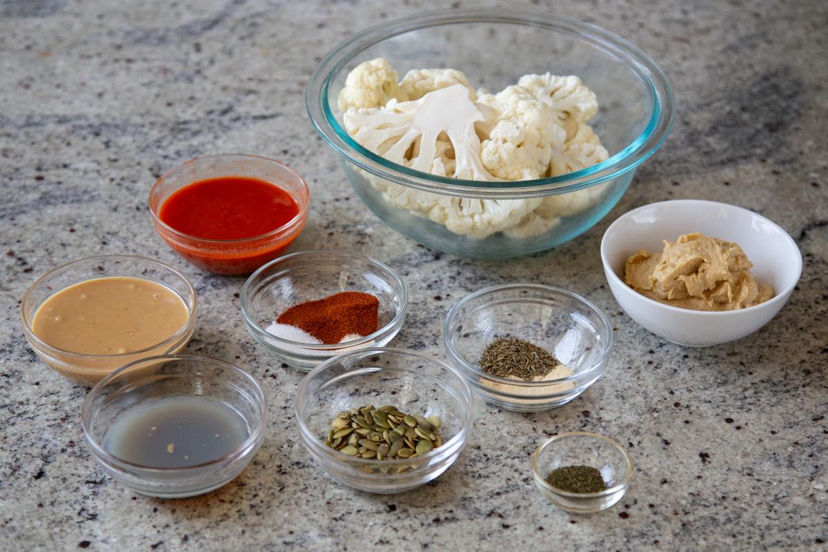 cauliflower, harissa paste, and other ingredients in bowls on a kitchen counter