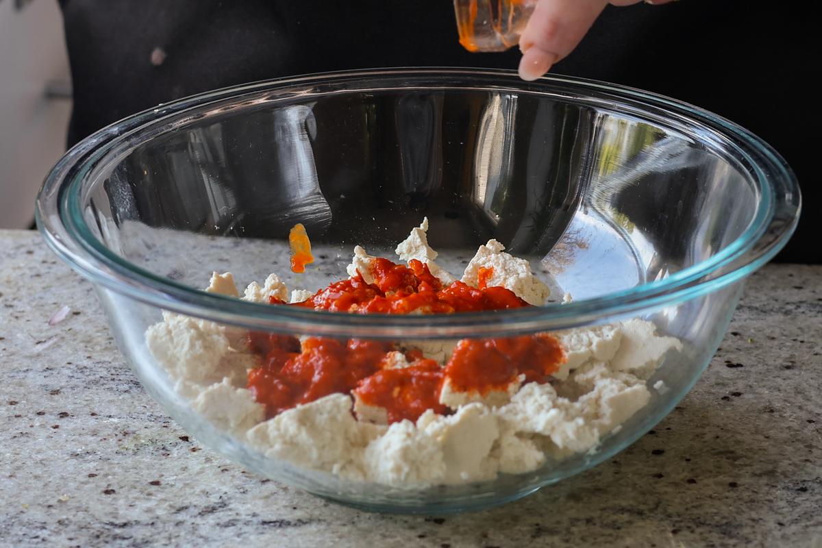 adding harissa to the tofu in the bowl