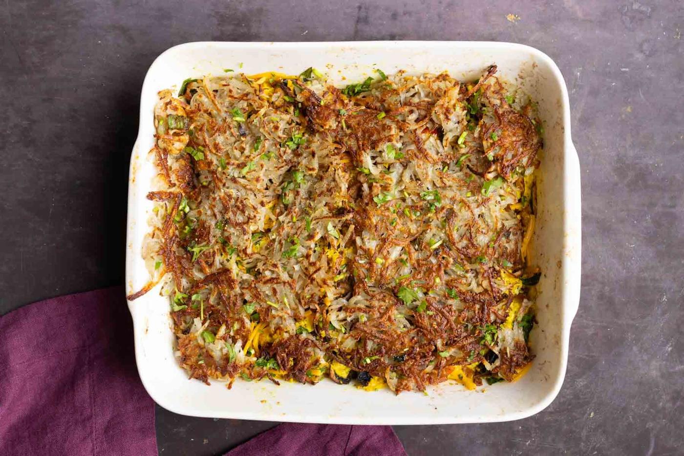 topping the vegan breakfast casserole with hashbrowns