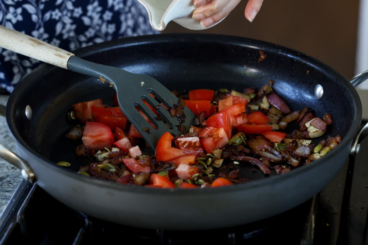 adding tomato and water to the pan