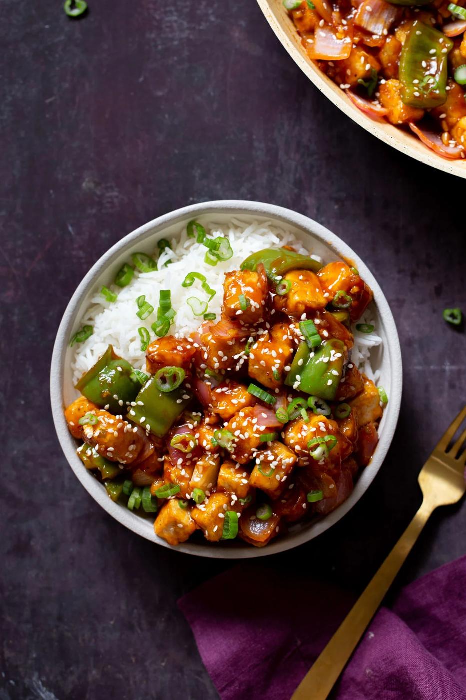 bowl of honey chilli tofu over rice next to the skillet