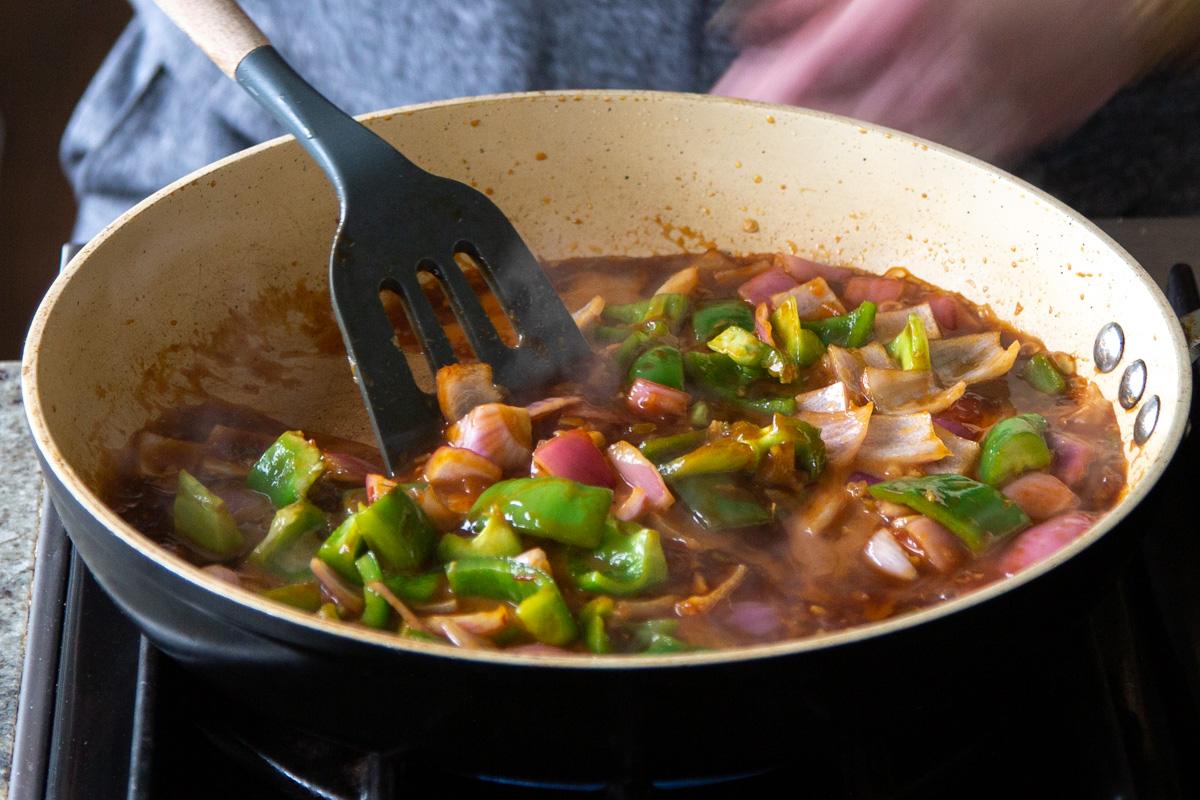 stirring cooked veggies in the pan with a spatula