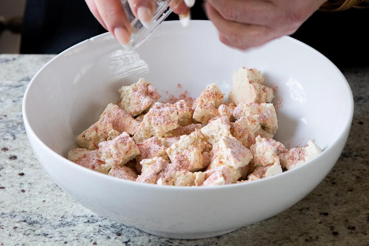 sprinkling cornstarch and spices onto the tofu