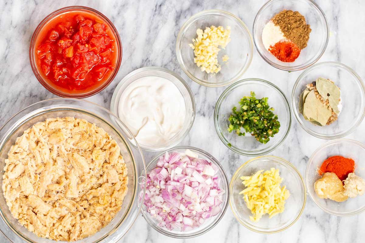 soy curls, ginger, tomatoes, and other curry ingredients in bowls on the kitchen counter
