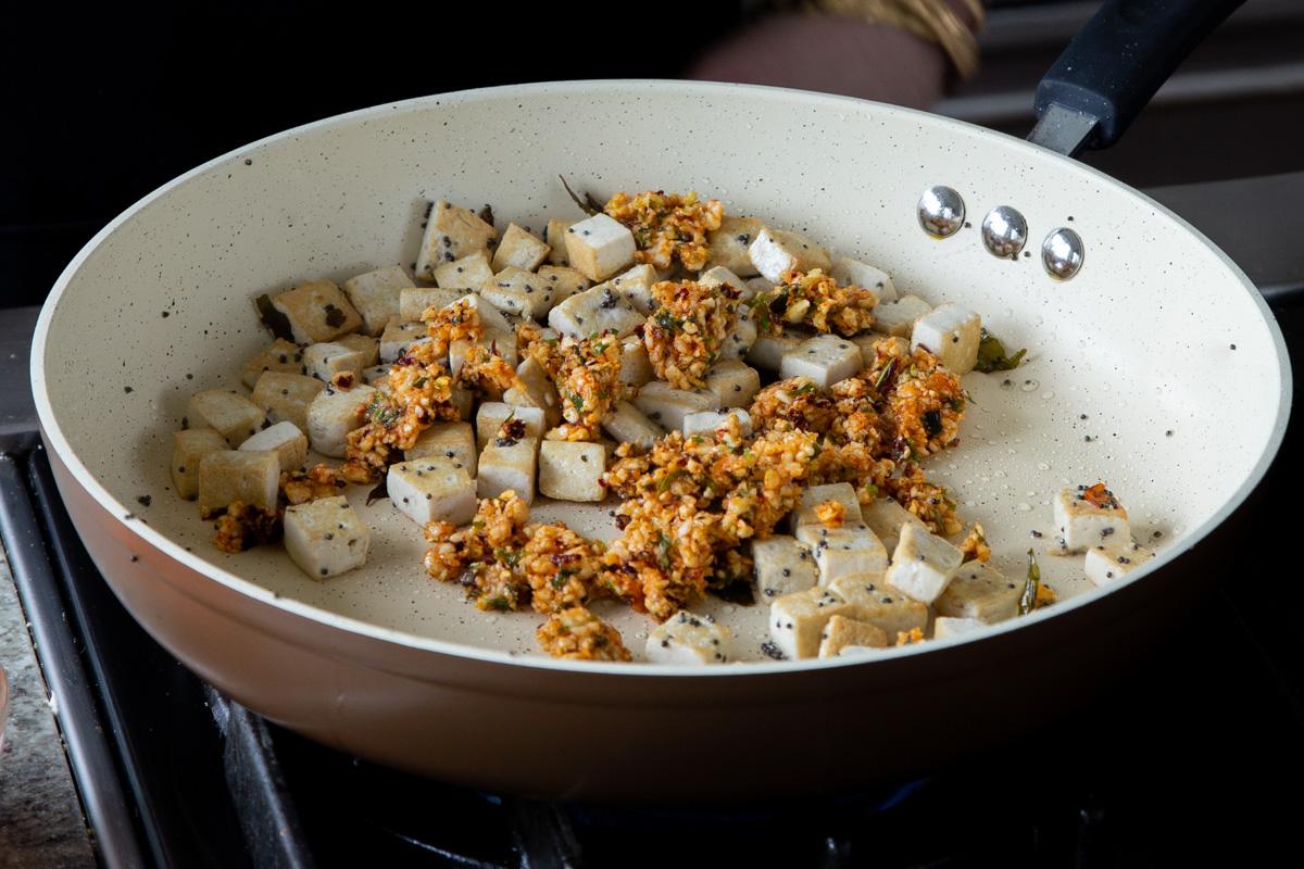 adding podi chutney to the pan with the tofu