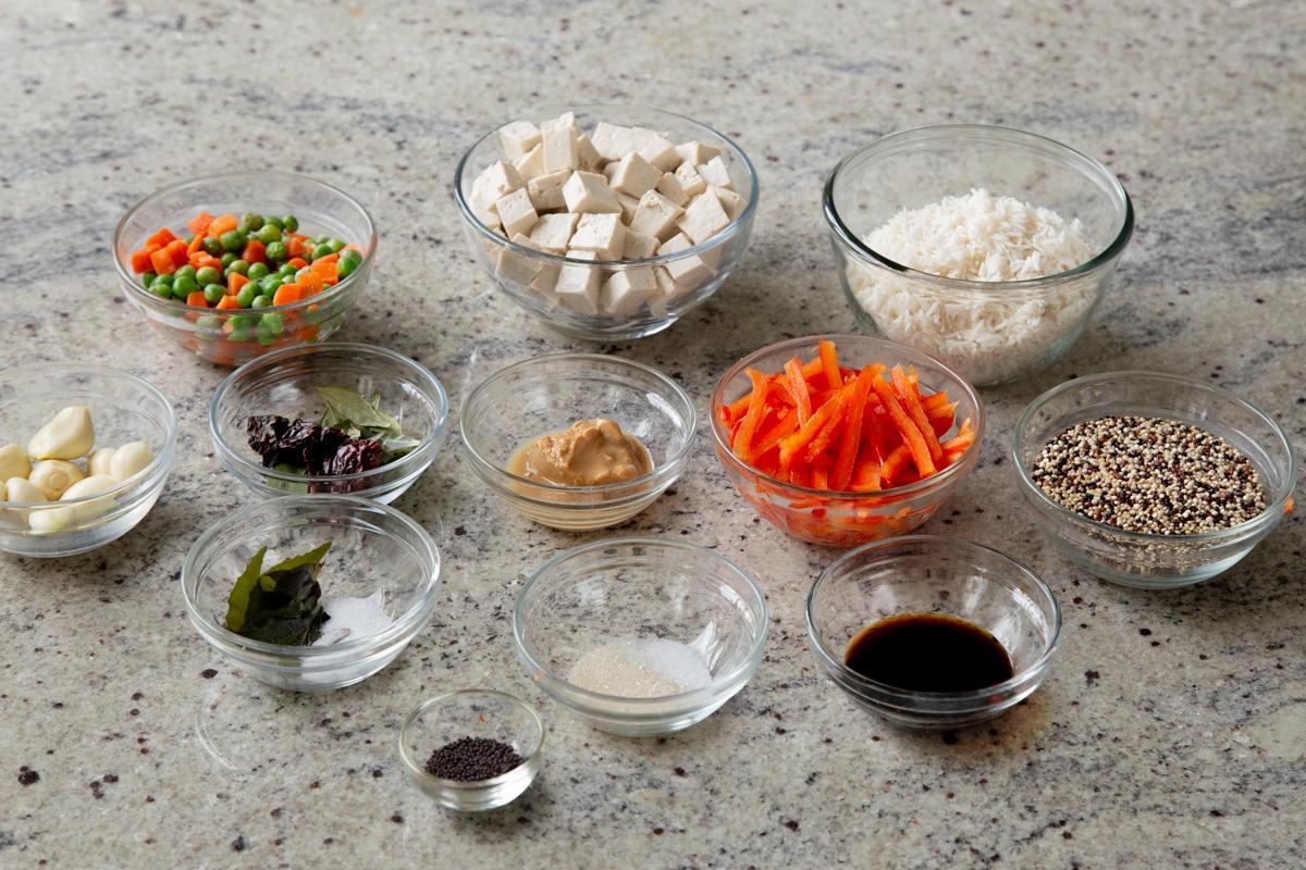 tofu, rice, veggies, and spices in bowls on a kitchen counter