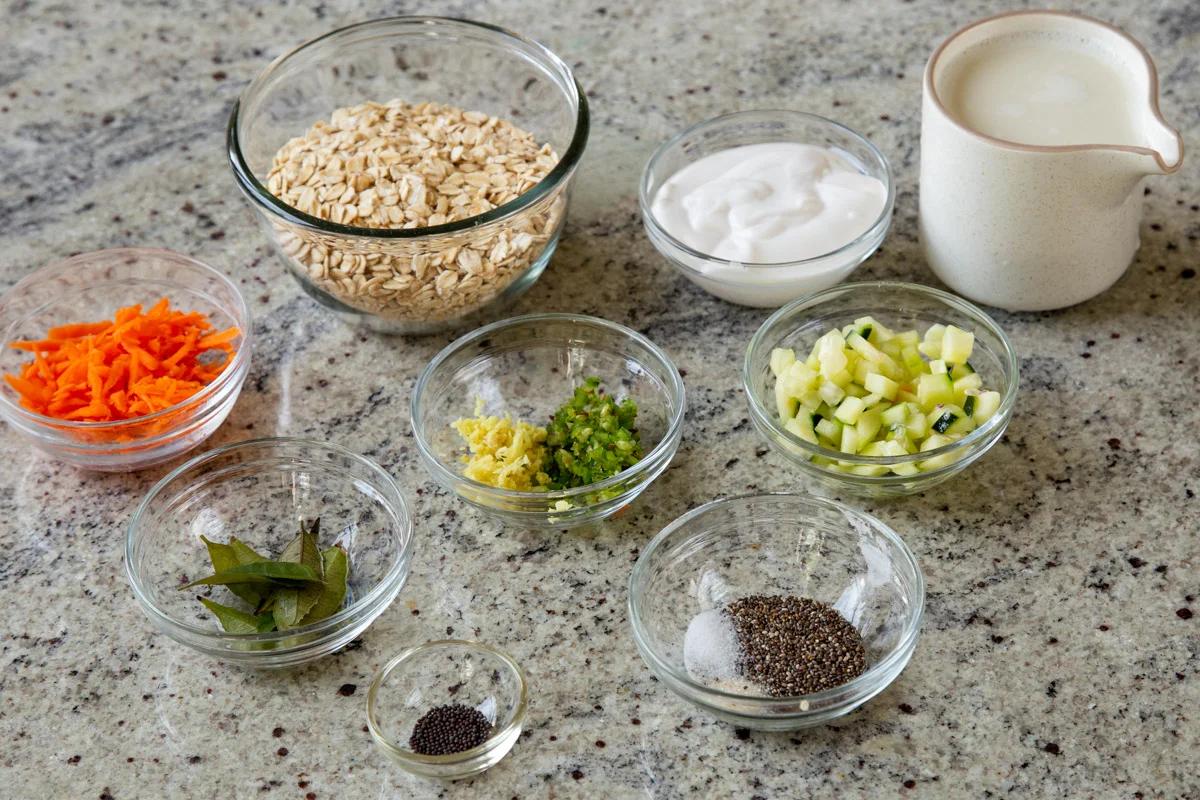 oats, nondairy yogurt, and other Indian savory overnight oats ingredients in bowls on a kitchen counter