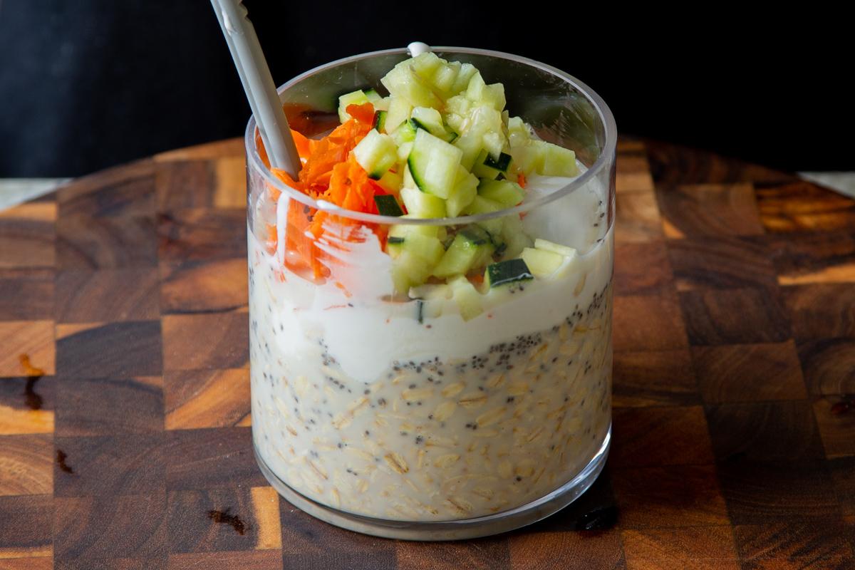 adding yogurt, carrots, and cucumber to the soaked oats and chia seeds