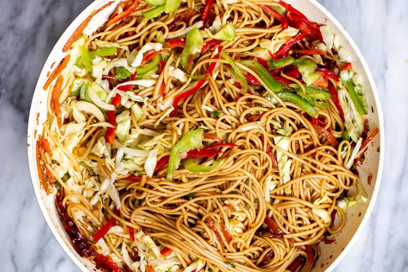 overhead shot of Indo Chinese Noodles in chili garlic sauce in a white pan