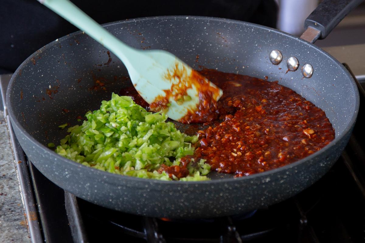 adding bell peppers to the sauce ingredients in the pan