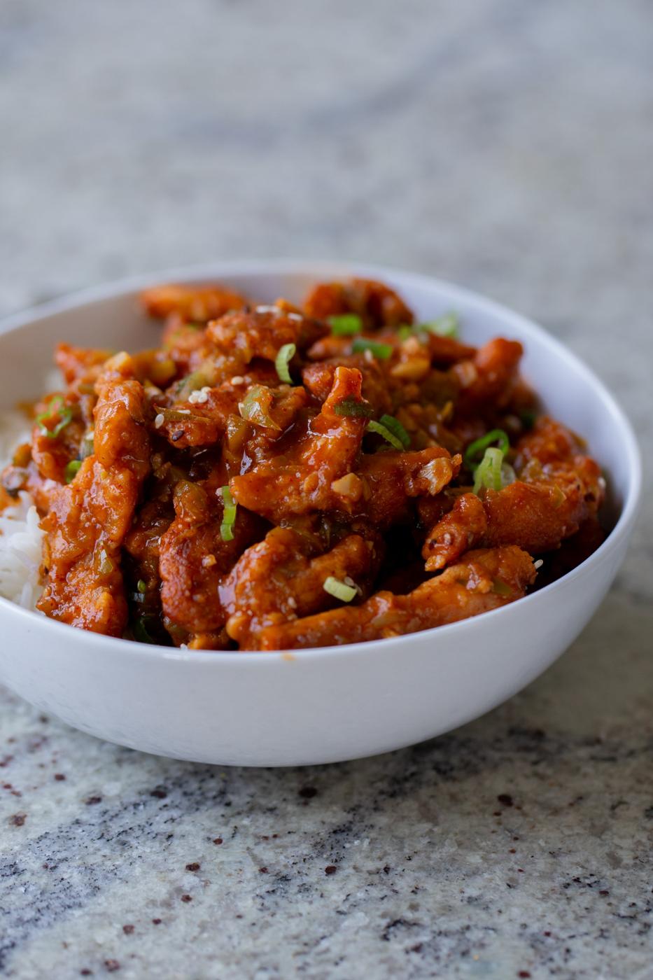 crispy Indo Chinese chicken in a bowl with rice and green onions