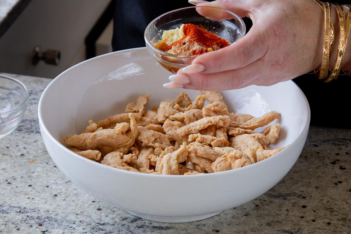 adding spices to the bowl of soy curls