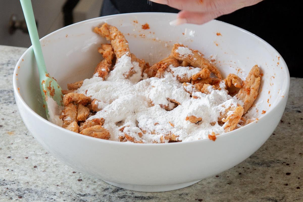 adding cornstarch, baking powder, and flour to the bowl of soy curls