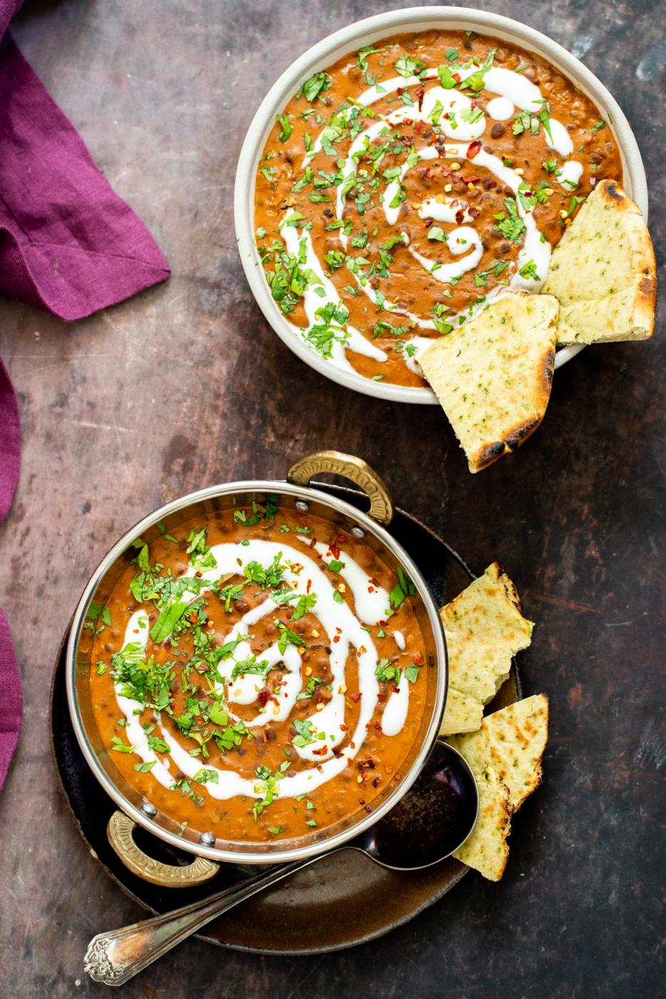 two Indian serving plates of dal bukhara drizzled with cashew cream