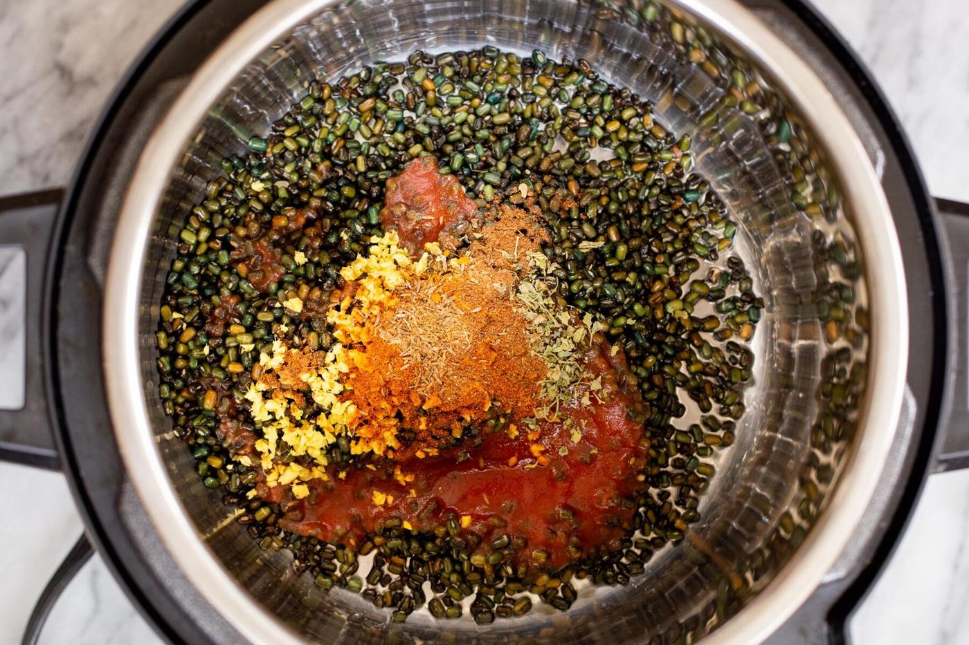 black gram being added to an instant pot along with spices and tomato paste