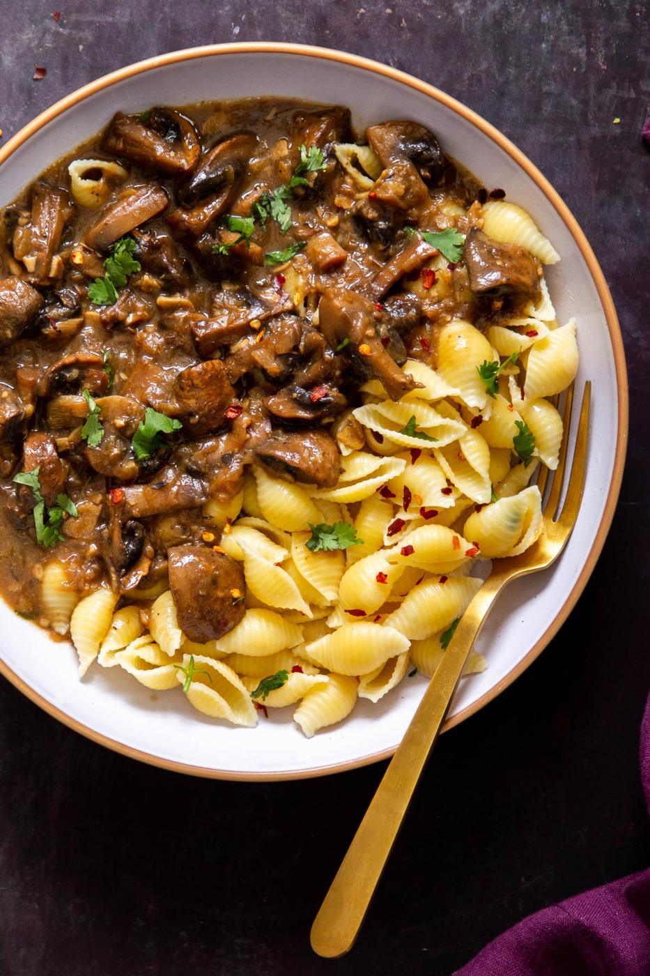 a white bowl with vegan Instant Pot garlic mushrooms served alongside shell pasta