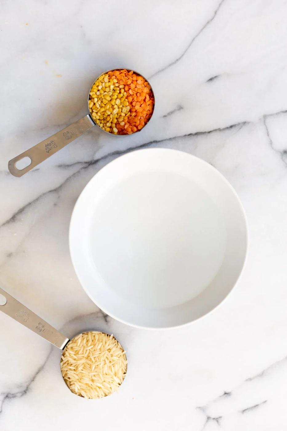 overhead shot of basmati rice dal split mung beans and red lentils next to a bowl of water