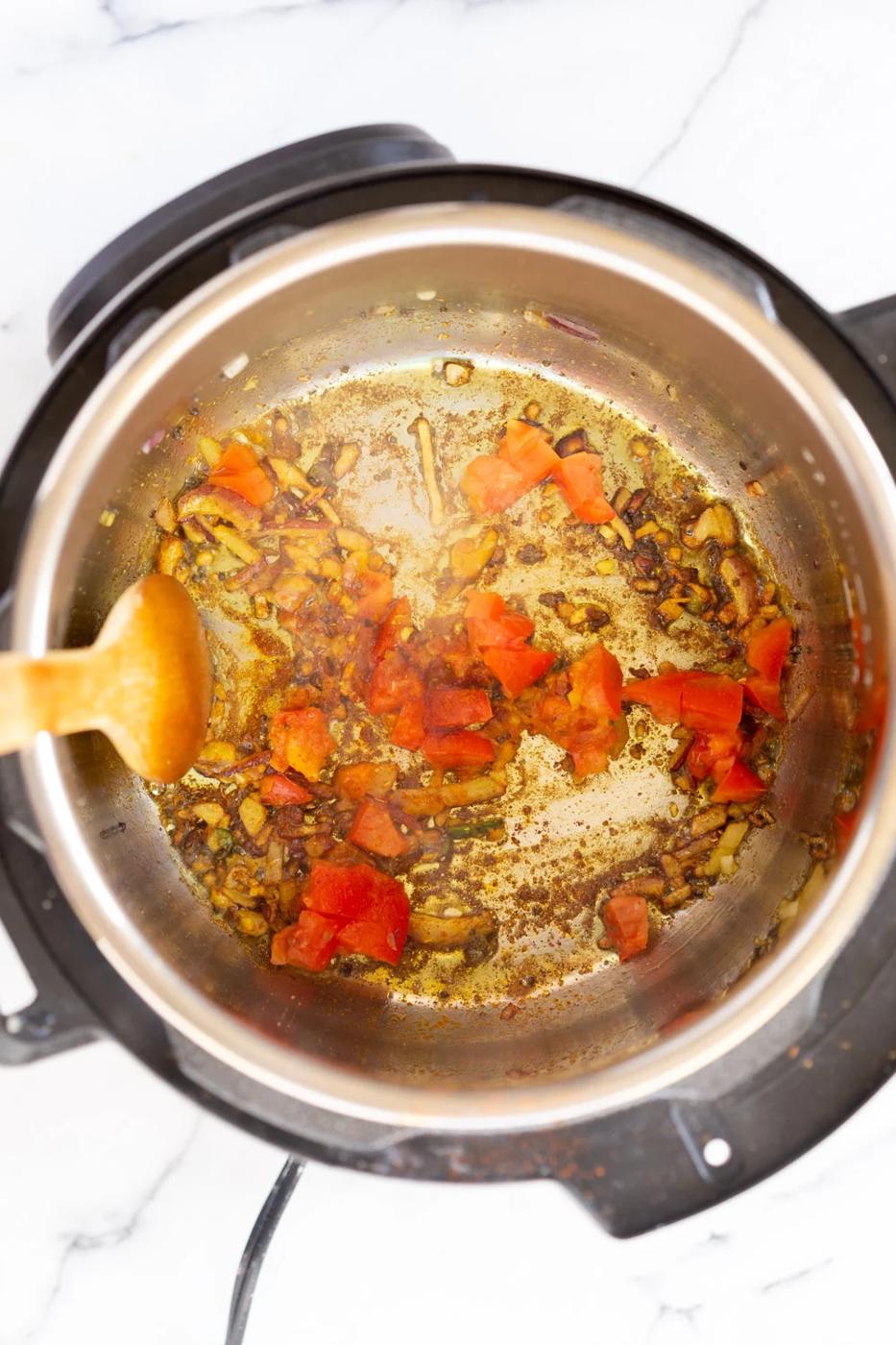 onions, garlic and spices being fried in an Instant Pot to make Kitchari