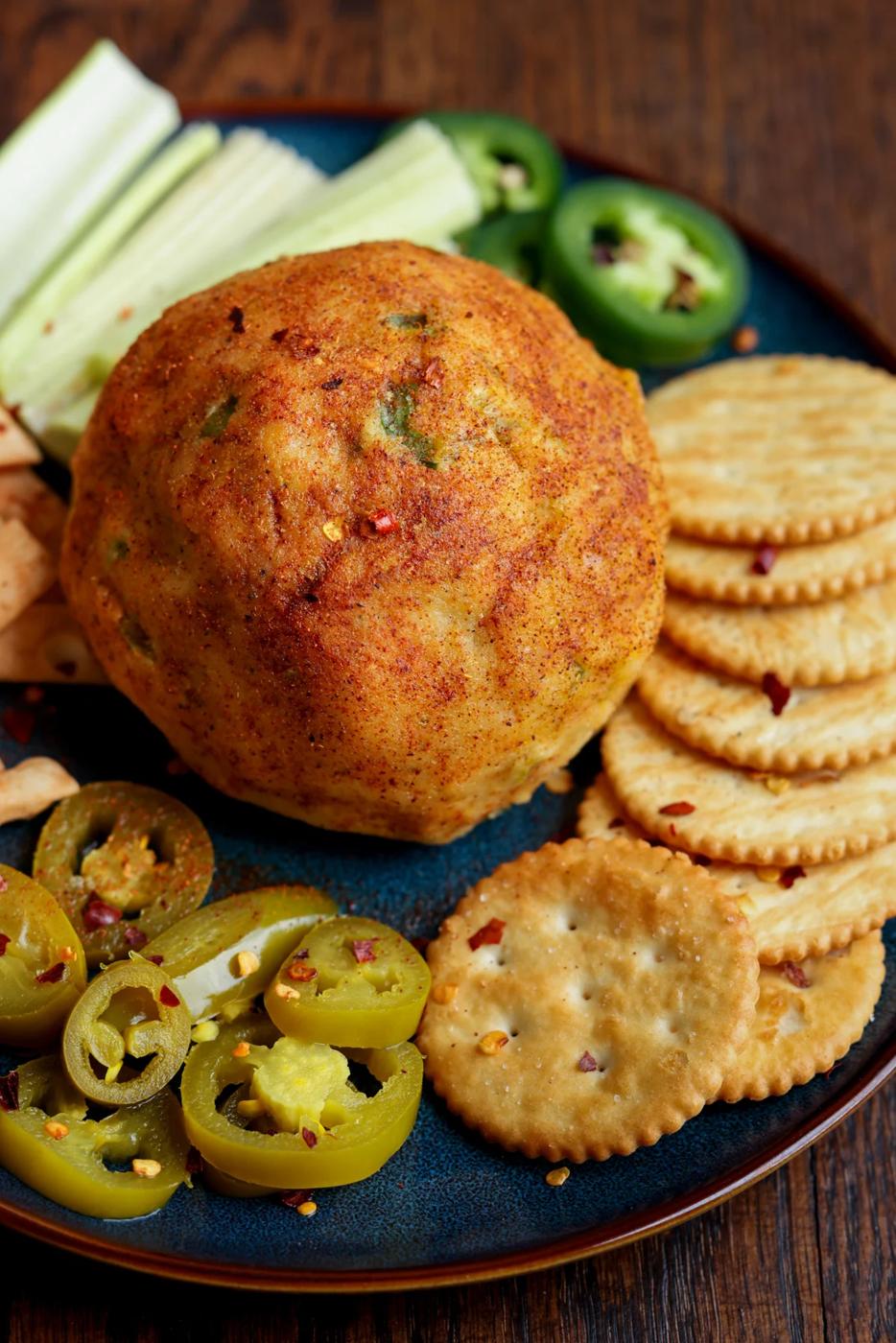 jalapeno popper cheese ball on a serving tray with crackers and veggies